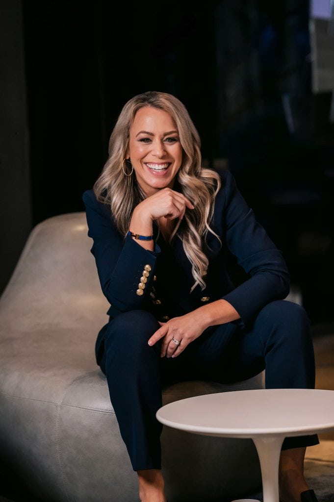 Empowered woman smiling in professional blazer, representing success and coaching expertise.