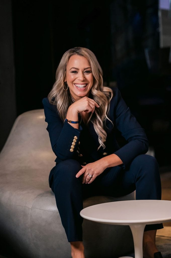 Confident woman in business attire smiling, representing leadership and coaching services at Full Pocket Coaching.