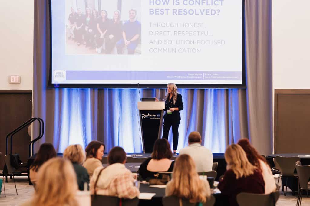 Leadership keynote speaker and Fractional COO facilitating a workshop with a dental leadership team during a conference session.