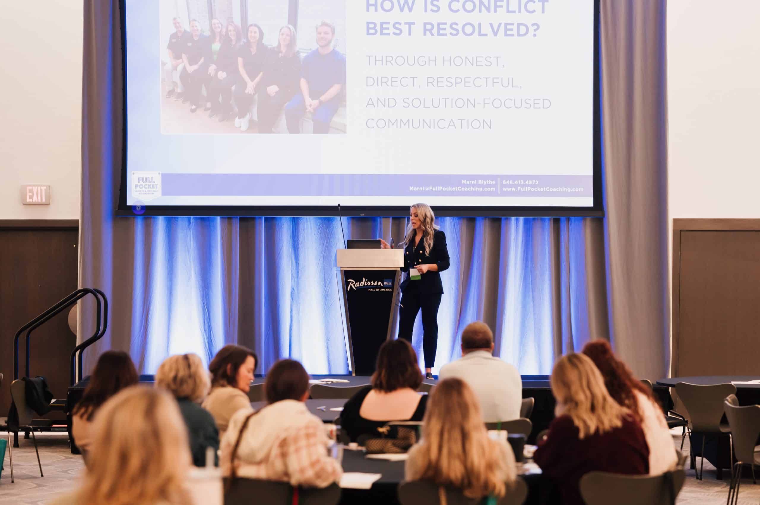 Leadership keynote speaker and Fractional COO facilitating a workshop with a dental leadership team during a conference session.